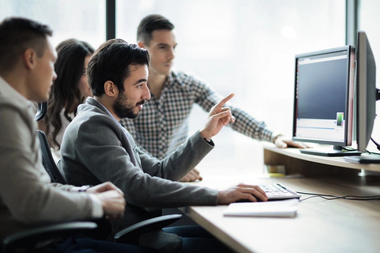 A group of people sitting at a table with computers.