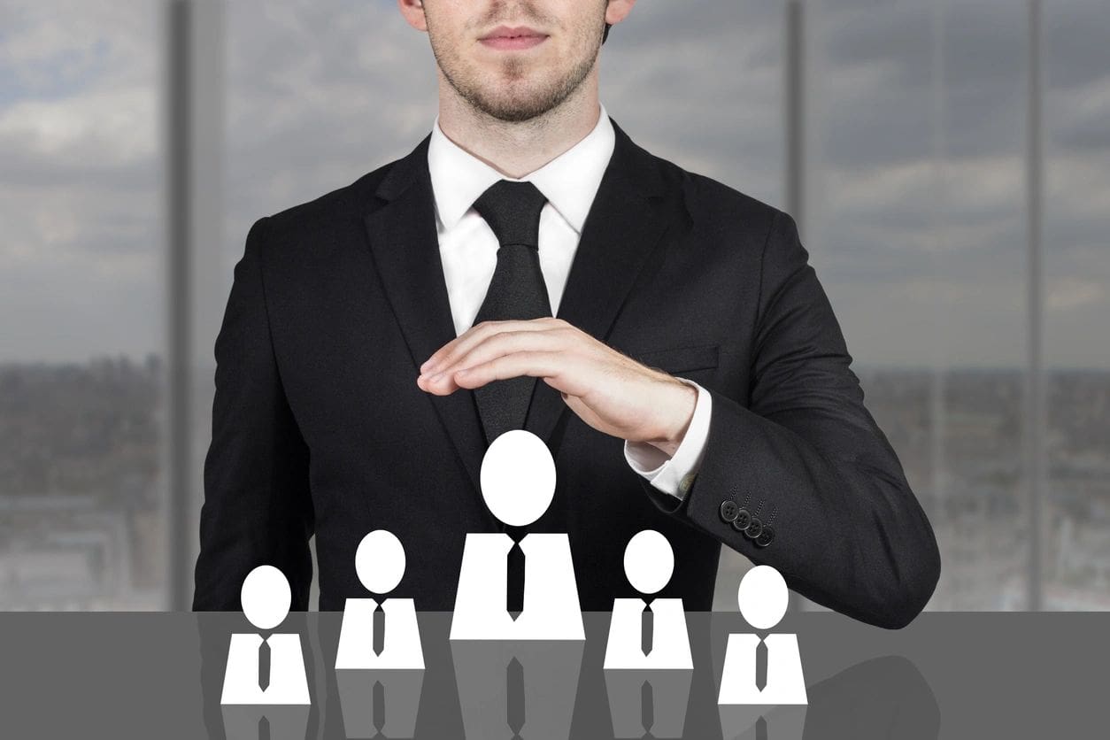 A man in a suit and tie standing next to some people.